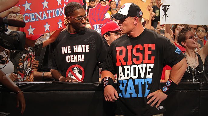 John Cena wearing a Rise Above Hate shirt beside anti-Cena fan messaging
